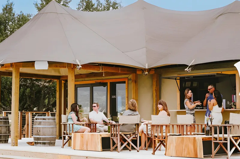 Guests seated on the deck of a safari tent lodge at Outdoorsy Hill Country