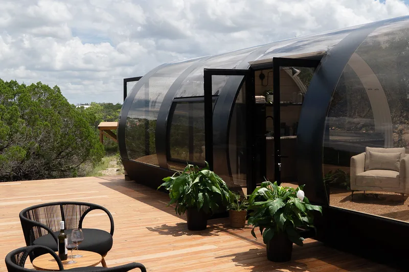 A curved glass and steel guest unit on a timber deck at Lagom Retreat