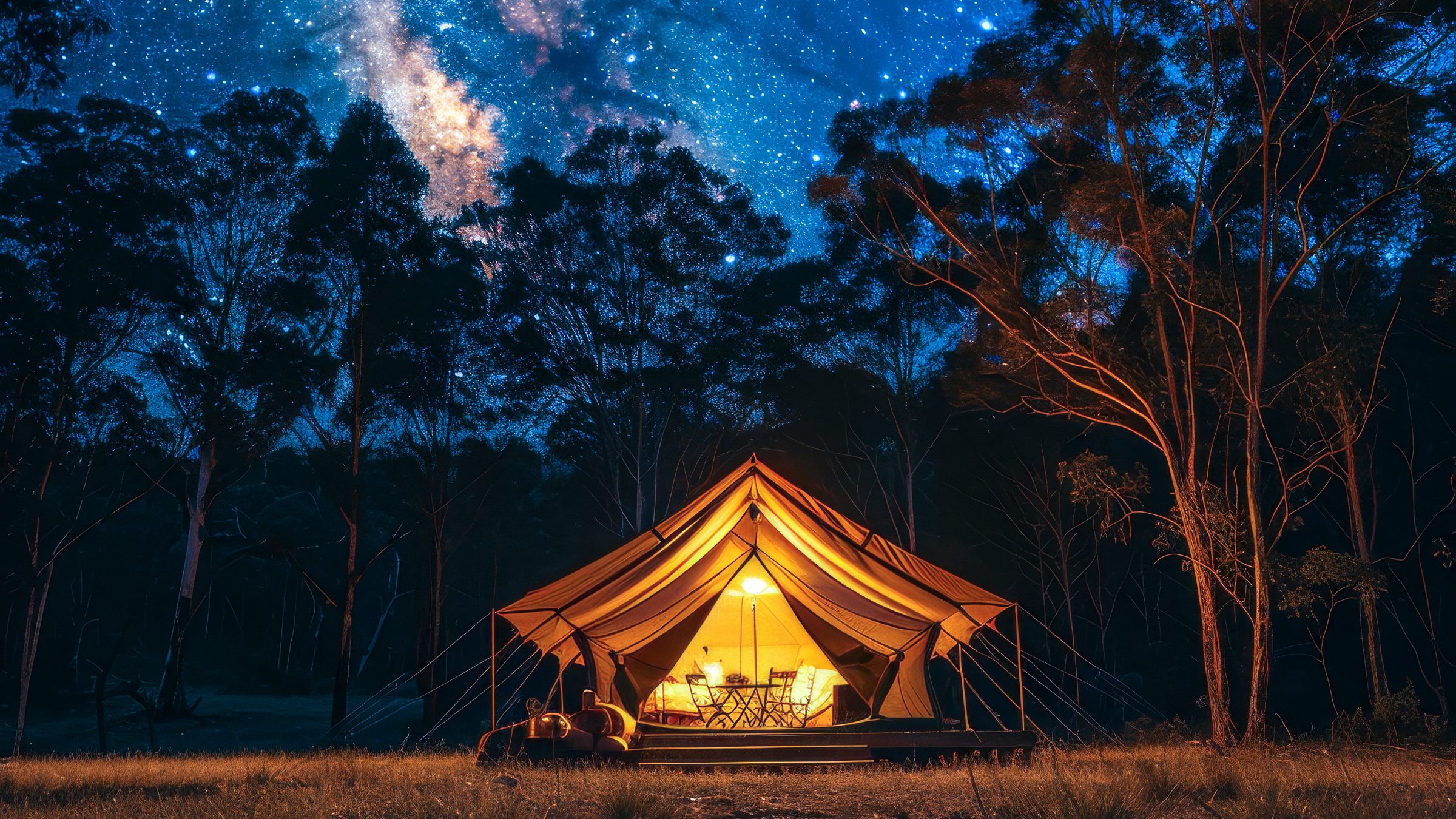 A lit safari tent glowing under the Milky Way in a eucalyptus clearing at night